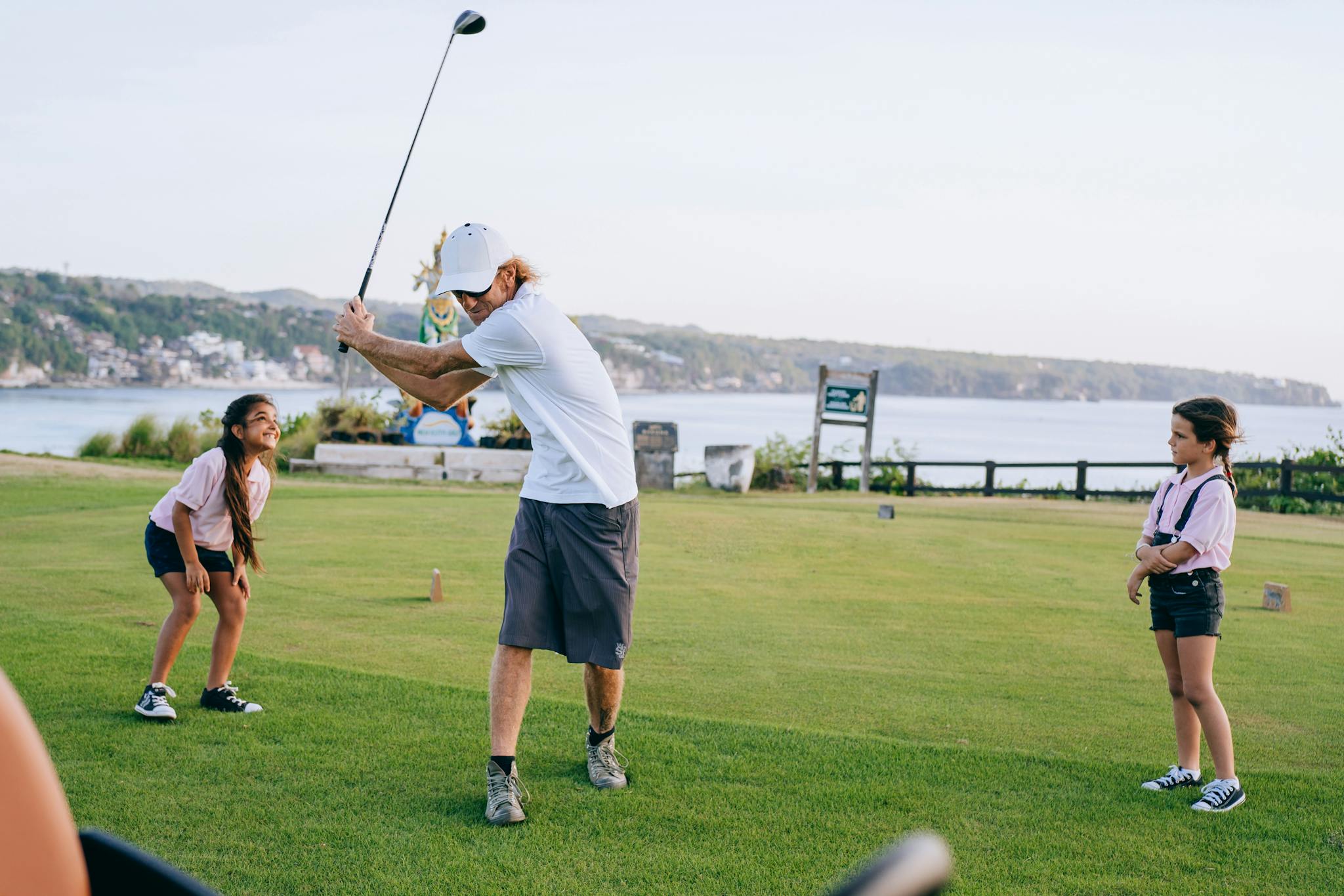 A family enjoying a round of golf on a picturesque outdoor course by the sea.