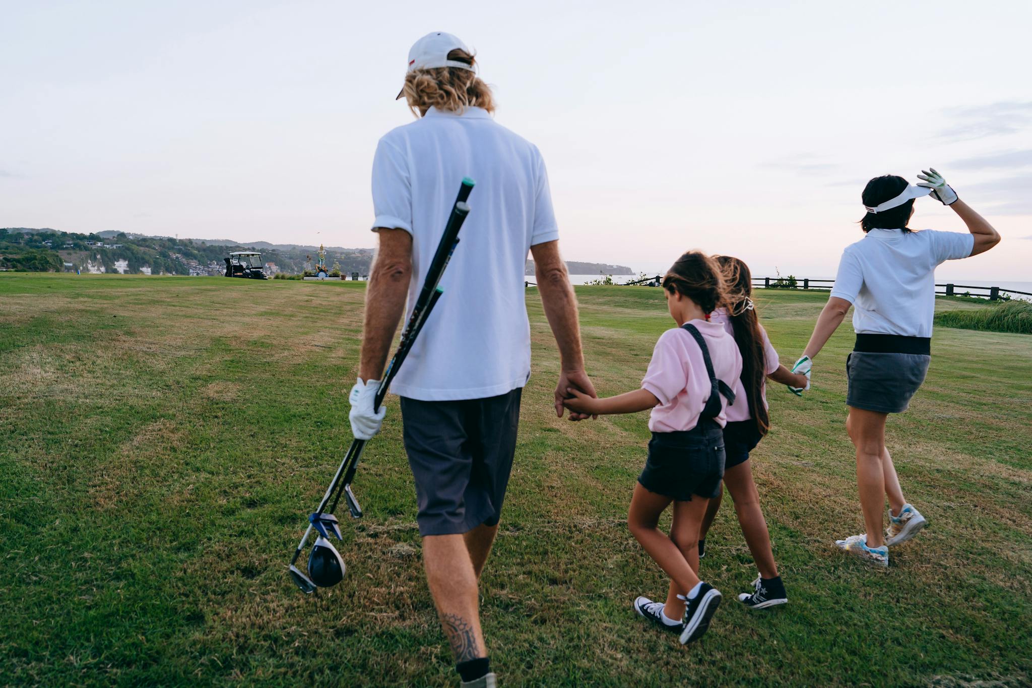 Family with children walking on a golf course enjoying leisure time together.